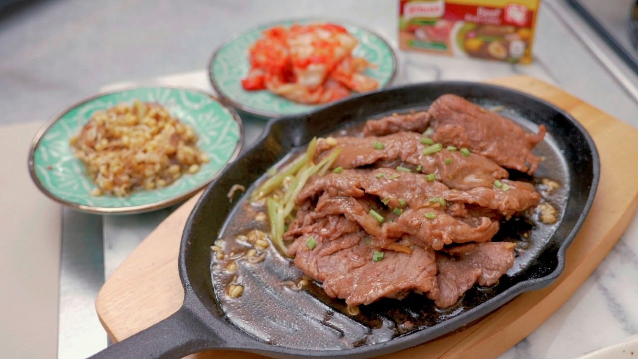 Beef bulgogi served on a sizzling plate with kimchi and stir-fried bean sprouts on the side