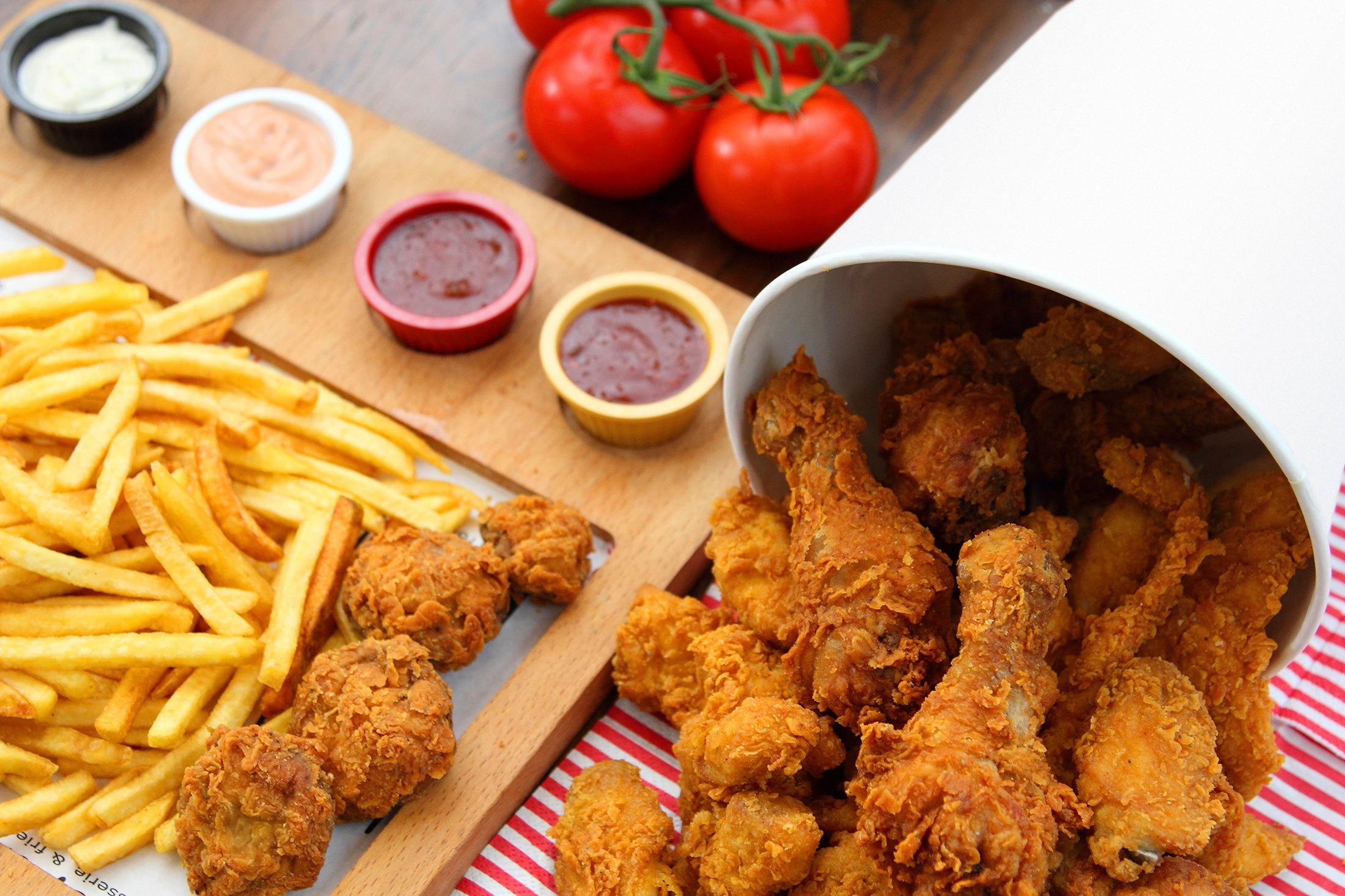 A bucket of fried chicken, served with french fries, ketchup, mayo, and Thousand Island dressing
