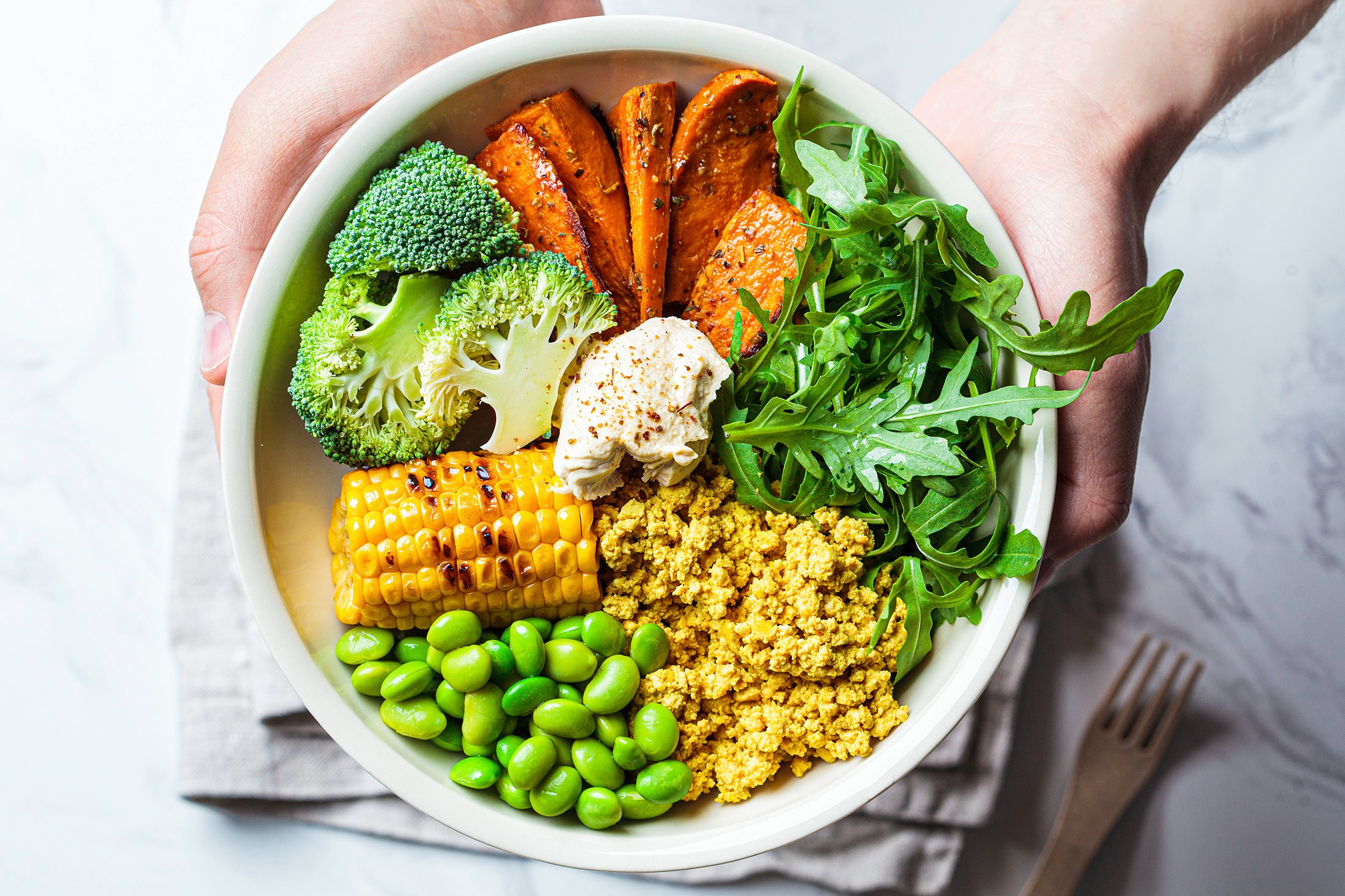 A bowl of roasted high-protein vegetables, including broccoli, corn, and edamame