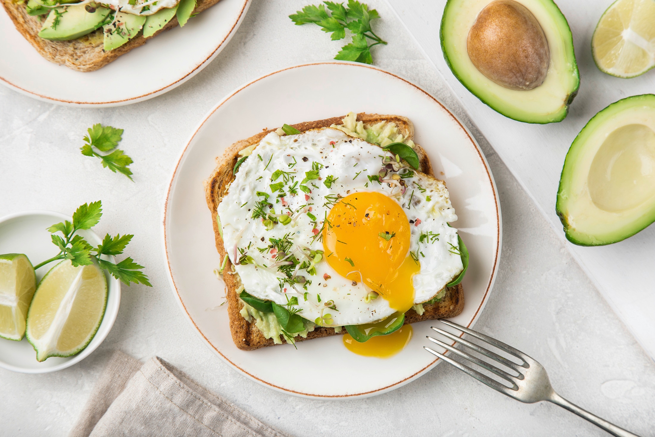 Avocado toast with greens, a fried egg, and herbs