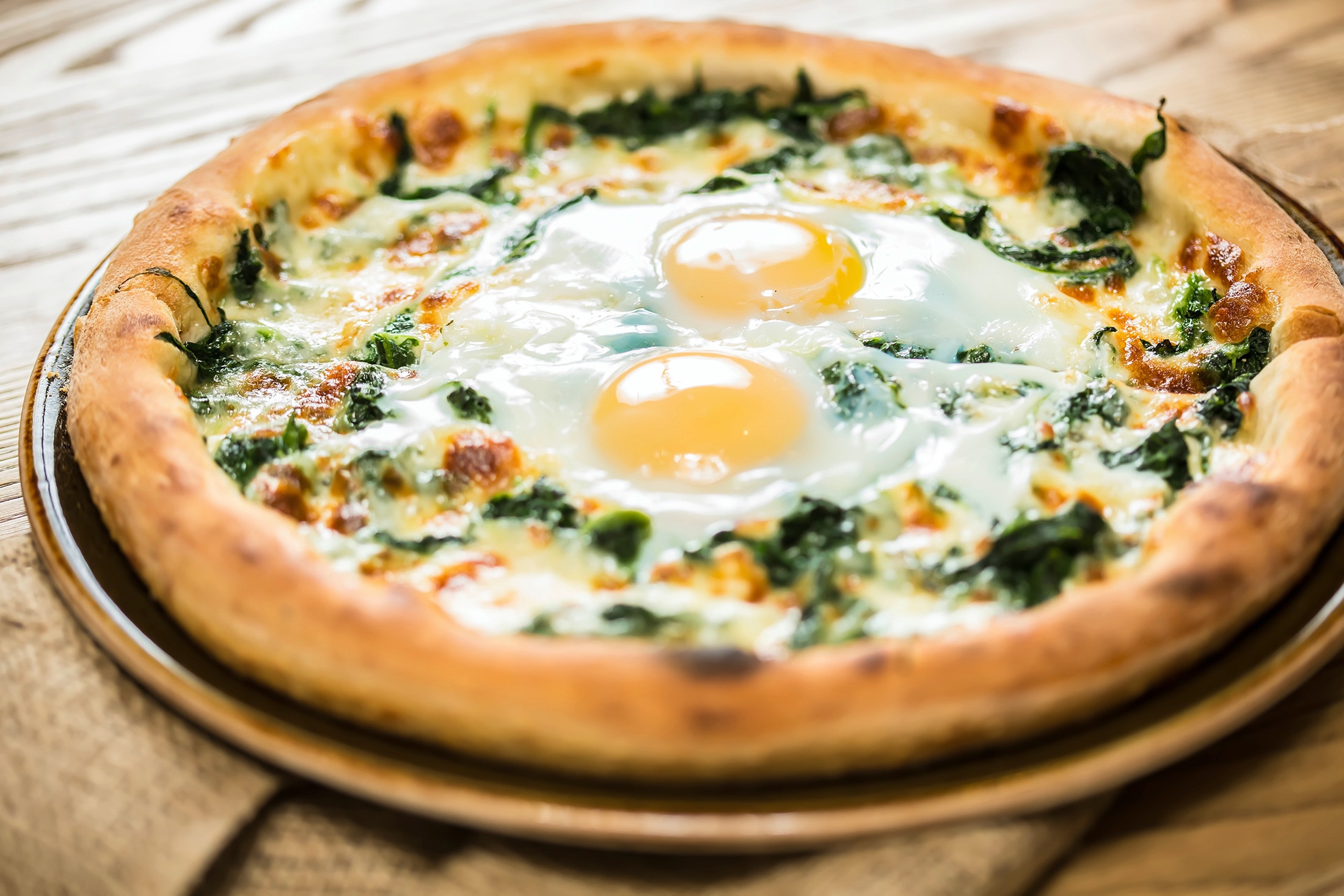 A Margherita pizza with arugula and two fried eggs