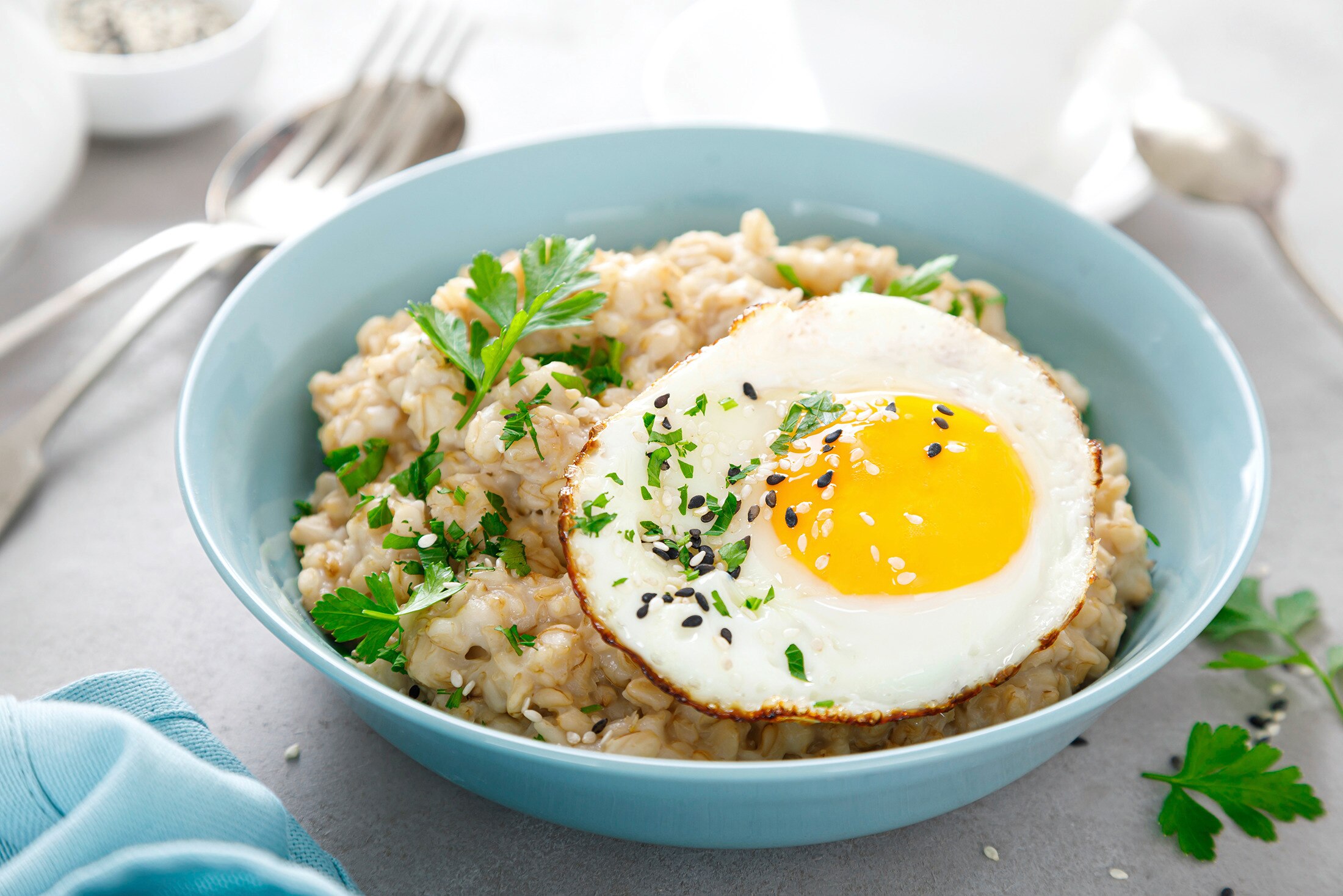 A bowl of savory oats with an egg on top, garnished with herbs