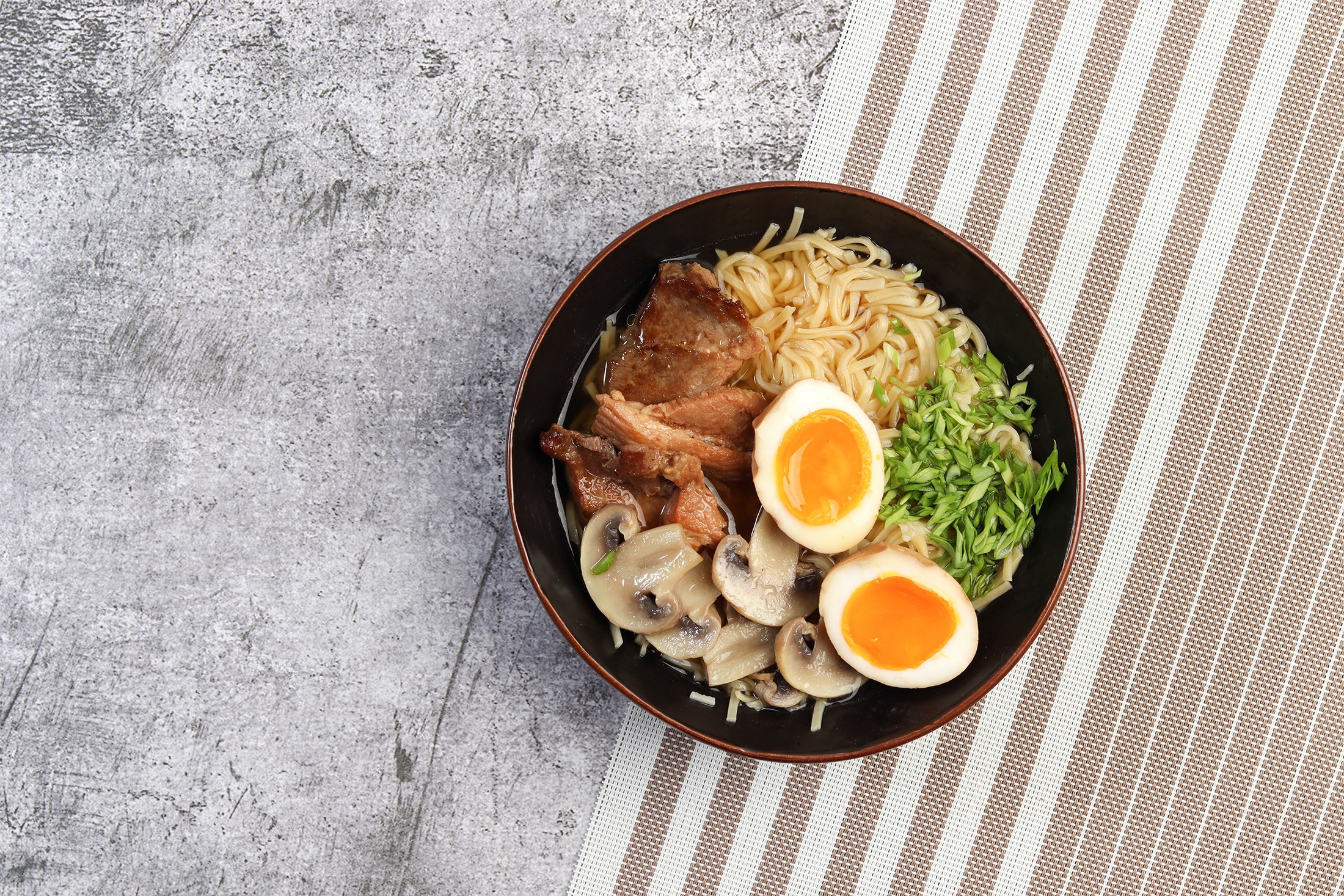 Ramen topped with pork belly, mushrooms, soft-boiled eggs, and spring onions